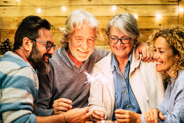 group of two seniors and two adults together having fun with sparlers the new year to celebrate - happy family with lights