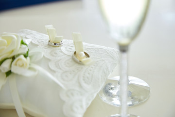 Two glasses of a champagne and pillow with wedding rings..
