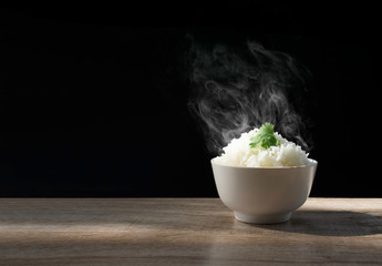 Cooked jasmine rice with hot steam and coriander on the top in white bowl