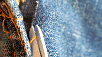Cut seam by scissors on blue jean fabric  in garment factory