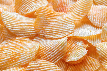 Background of corrugated fried potato chips. Top view, selective focus.