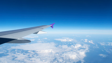 Fototapeta na wymiar Wing of an airplane flying above the clouds with blue sky, aerial view from the window of the plane,airtransportation make your life easy for travel.