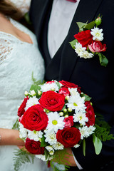 Wedding bouquet. The girl in a white dress and a guy in a suit sitting are holding a beautiful bouquet flowers and greenery. Unrecognizable