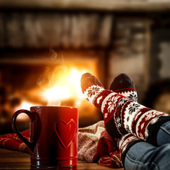 Woman legs with christmas socks and fireplace in home interior. 