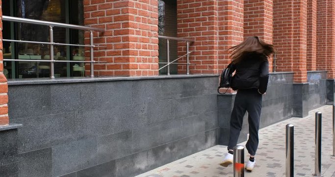 the girl is wearing a new jacket and a red sweater. it passes next to the office building. 4k proress 50p