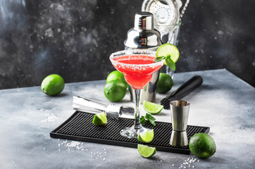 Watermelon margarita, alcoholic cocktail with silver tequila, lime juice, mint, watermelon and crushed ice, metal bar tools, gray background