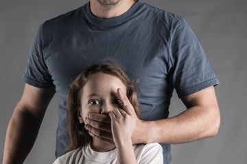 Male hands on little crying girl, concept of children exploitation.