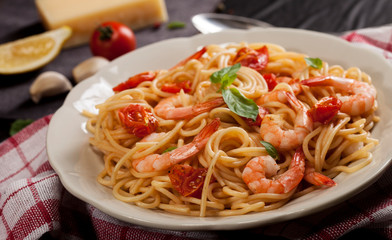 Pasta spaghetti with shrimps, dried tomato and basil on black background. Healthy meal. Italian food.