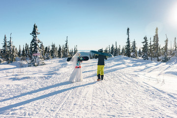 Wedding couple with snowboards in the snowy mountains