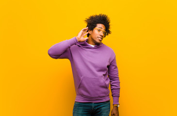 young black man looking serious and curious, listening, trying to hear a secret conversation or...