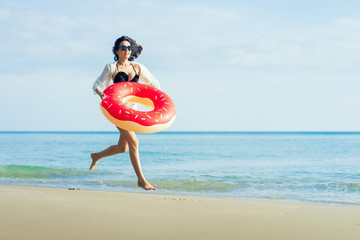 Naklejka na ściany i meble Happy asian woman enjoying freedom on a beach at sunset