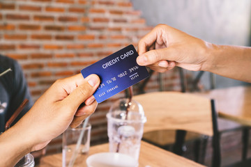 man hand paying his drinks by credit card at coffee shop