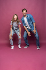 Active young couple of friends having good time, dancing, laughing together on pink background