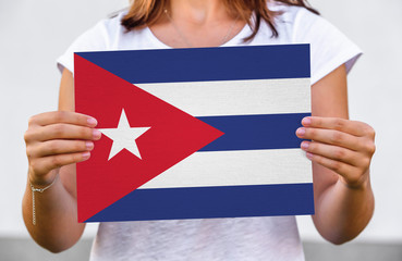 woman holds flag of Cuba on paper sheet