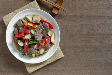 top view of stir fried beef with oyster sauce in a ceramic dish on wooden table. asian homemade style food concept.