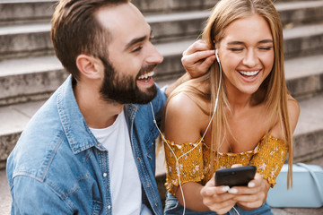 Smiling lovely young couple sitting together on stairs