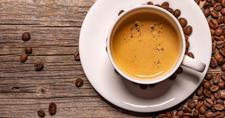 White cup of aromatic black coffee on a wooden table.