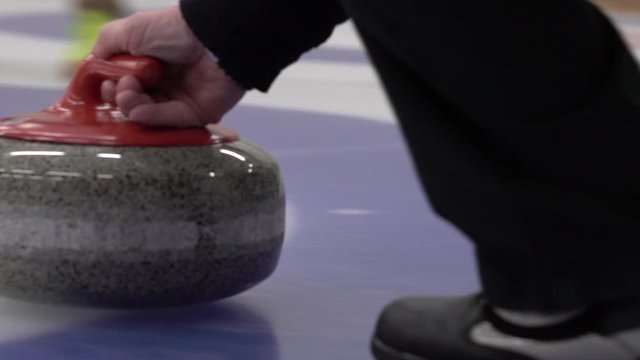 Curler is sliding with curling stone on pebbled ice sheet. Winter team game, winter olympic sport.