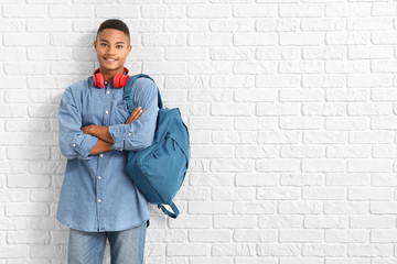 Portrait of African-American teenage schoolboy on brick background