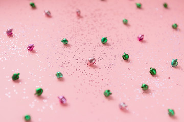 pink and green jingle bells on pink background with glitter - selective focus - Christmas festive pastel backdrop