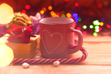 Christmas composition with the lights. Cup of coffee, beautiful toys, gifts and candy on the wooden background. New year background.  Close up. Space for a text.