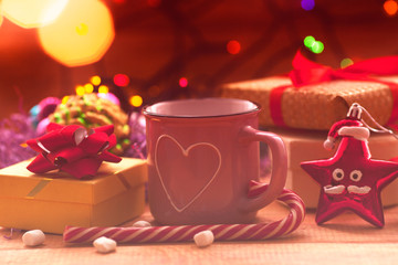 Christmas composition with the lights. Cup of coffee, beautiful toys, gifts and candy on the wooden background. New year background.  Close up. Space for a text.