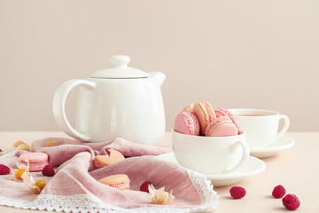 Tasty macarons with tea on table