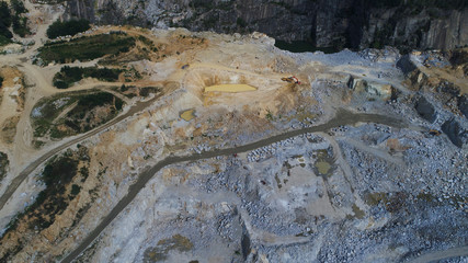 Aerial view of opencast mining quarry with lots of machinery at work, excavators and drills. 4K footage from above