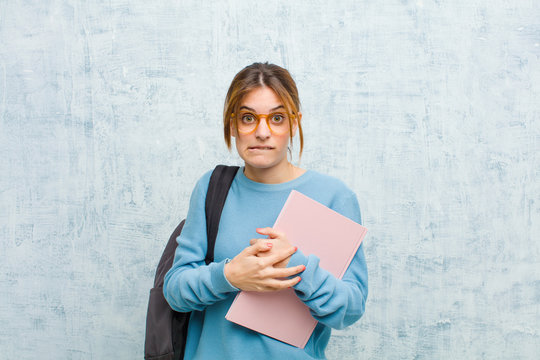 young student woman feeling clueless, confused and uncertain about which option to pick, trying to solve the problem against grunge wall background
