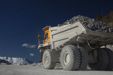 Heavy dump-body truck filled with ore close-up against a dark blue sky. Mining equipment. Quarry equipment.