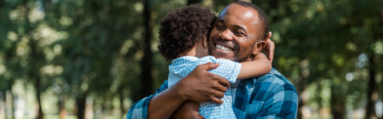 panoramic shot of happy african american father hugging son