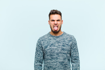 young hispanic man feeling disgusted and irritated, sticking tongue out, disliking something nasty...