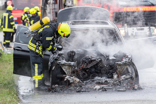 Feuerwehrmann kontrolliert mit Wärmebildkamera brennendes Auto