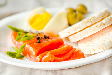 Slices of Salted Raw fish fillet with egg and rice cakes. Selective focus. Paleo diet meal. Healthy high protein and low carbohydrate products concept.