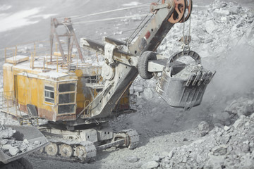 Excavator in a quarry during loading dump-body truck, close-up, tilt-shift lens effect. Quarry equipment. Mining equipment.