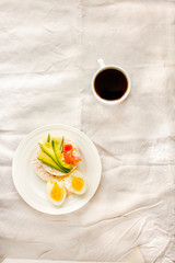 Rice crispy cakes with avocado and fresh salted salmon.Top view. Space for text. High protein and low carbohydrate meal. White linen tablecloth background
