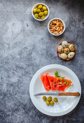 Smoked red fish salmon with olive, quail eggs, nuts and rice crispy cakes with avocado on a gray background. Top view. Rustic. Products with omega-3 good for healthy hair and skin