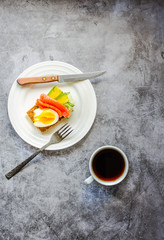 Gluten-free toast with avocado and fresh salted salmon, eggs and cuo of coffee on a gray background. Top view. Space for text. High protein and low carb meal