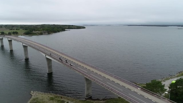 Aerial view of Scandinavian landscape and bridge. Cars and motorcycles driving through the long modern bridge.	