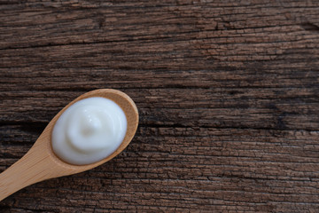 Natural homemade plain organic yogurt in wood spoon on wood texture background