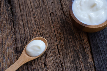 Fototapeta na wymiar Natural homemade plain organic yogurt in wooden bowl and wood spoon on wood texture background