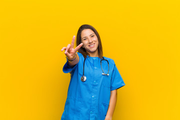 smiling and looking happy, carefree and positive, gesturing victory or peace with one hand isolated...