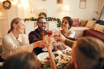 High angle portrait of cheerful adult people clinking champagne glasses while enjoying Christmas...