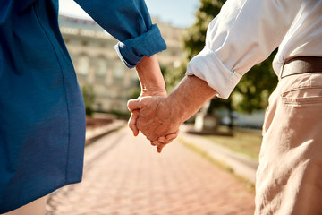 You and me forever. Close-up of elderly couple holding hands while walking together outdoors - Powered by Adobe