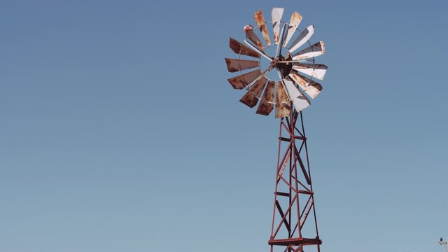 Medium Panning Shot from an Old Rusty Wind Pump Going Up to the Sky