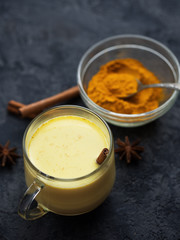 Indian spice turmeric Golden milk in a mug on a dark stone table