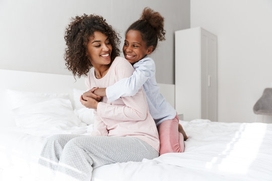 Image Of African American Woman And Her Little Daughter Hugging In Bedroom