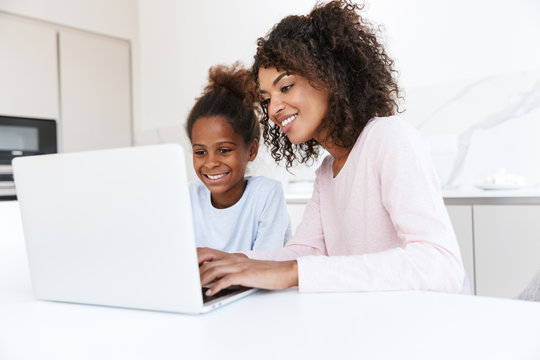 Image of african american woman and her daughter using laptop at home