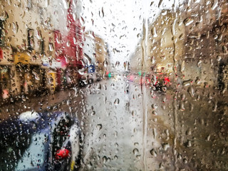 Close up of raindrops on wet glass window of a tram and the view to the street and traffic on a rainy day