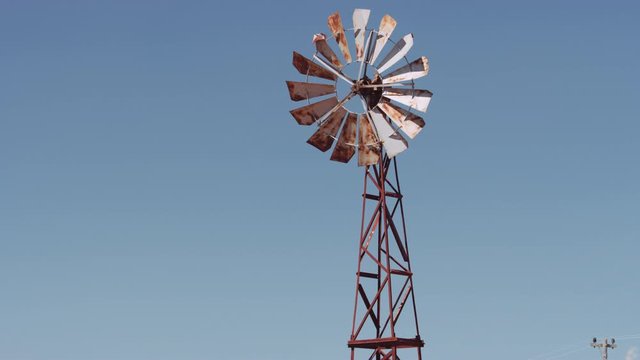 Camera Tilting Down to Reveal an Old Rusty Wind Pump